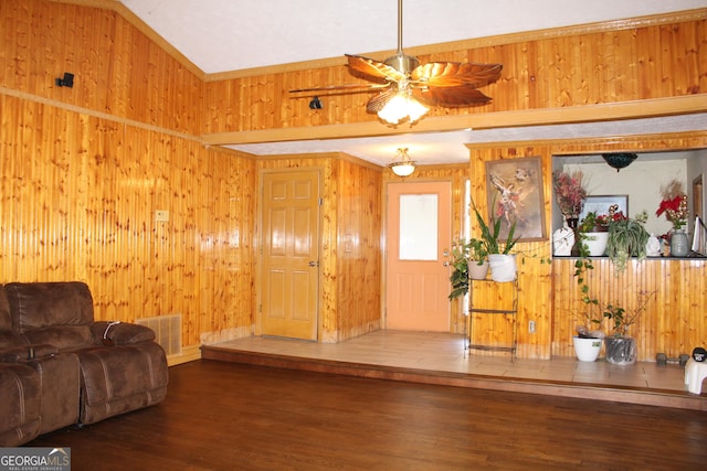 living room featuring a ceiling fan, wood finished floors, visible vents, and wood walls