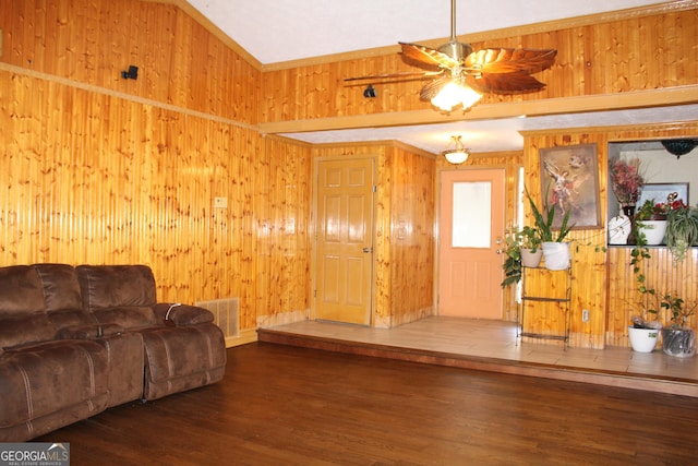 living area featuring a ceiling fan, wooden walls, wood finished floors, and visible vents