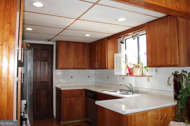 kitchen with dishwasher, light countertops, freestanding refrigerator, brown cabinetry, and a sink