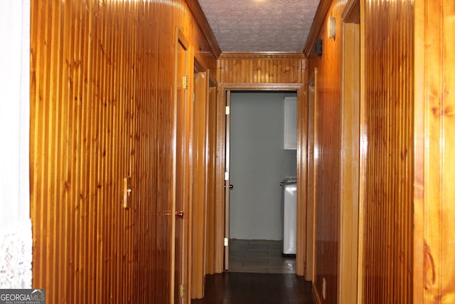 hall featuring crown molding, wood walls, and a textured ceiling