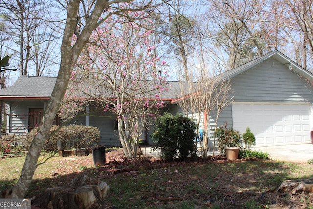 single story home with concrete driveway, a garage, and a shingled roof