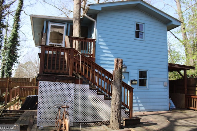 rear view of house featuring stairway, a wooden deck, and fence