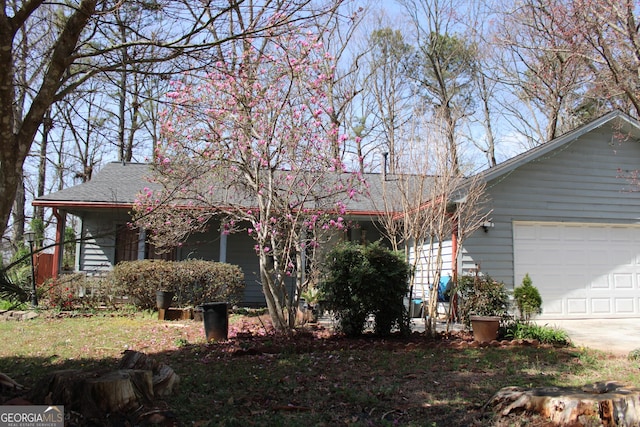 ranch-style home with driveway, an attached garage, and a shingled roof