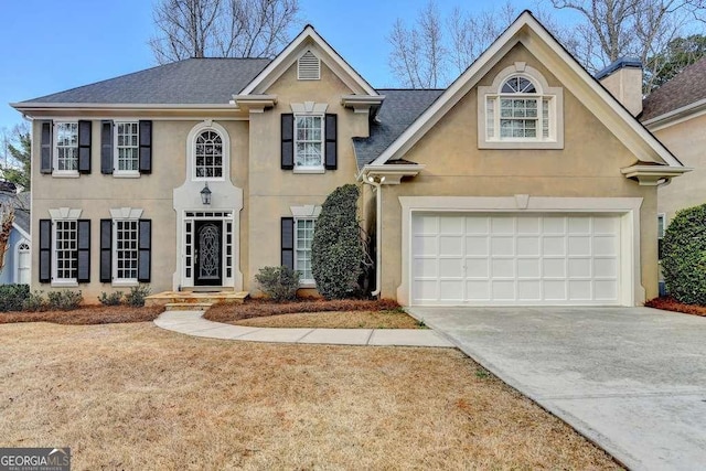 view of front of house with driveway, a shingled roof, a chimney, stucco siding, and a garage