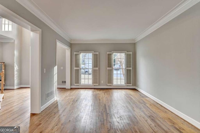 unfurnished room with visible vents, light wood-type flooring, baseboards, and ornamental molding