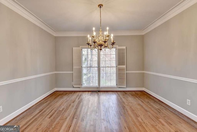 unfurnished room with a notable chandelier, wood finished floors, baseboards, and ornamental molding