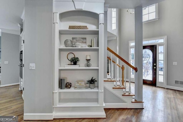 entryway with stairway, wood finished floors, visible vents, and baseboards