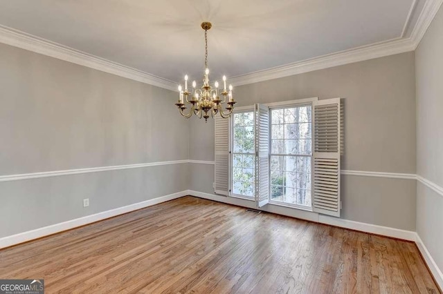 spare room with visible vents, ornamental molding, wood finished floors, an inviting chandelier, and baseboards