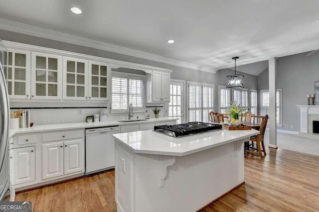 kitchen with a sink, a kitchen island, white cabinetry, glass insert cabinets, and dishwasher