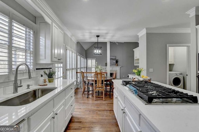 kitchen featuring gas cooktop, washer / clothes dryer, a sink, white cabinets, and light wood-style floors