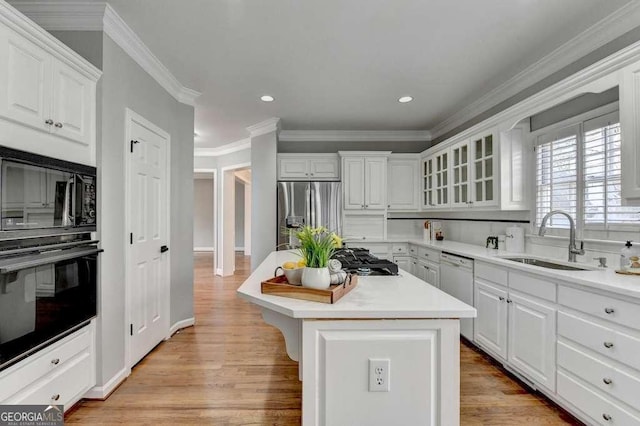 kitchen featuring black appliances, a sink, a center island, white cabinetry, and light countertops