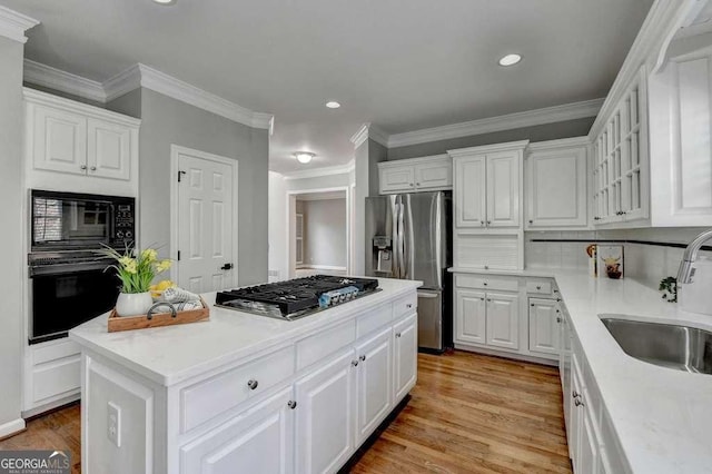 kitchen featuring a sink, light wood-type flooring, black appliances, and white cabinetry