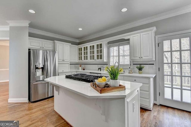 kitchen with a kitchen island, light countertops, light wood-style flooring, stainless steel refrigerator with ice dispenser, and white cabinetry