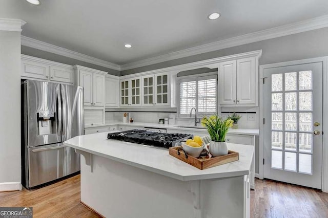 kitchen with a sink, a center island, white cabinetry, stainless steel fridge, and light countertops