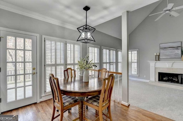 dining space featuring crown molding, baseboards, ceiling fan, a fireplace, and wood finished floors