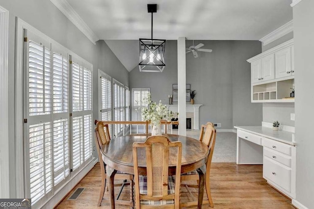 dining room featuring visible vents, light wood-style flooring, a fireplace, ceiling fan, and vaulted ceiling