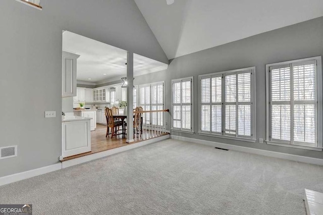 unfurnished living room featuring baseboards, a healthy amount of sunlight, visible vents, and light carpet