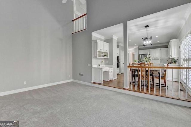 interior space with visible vents, baseboards, an inviting chandelier, ornamental molding, and light colored carpet