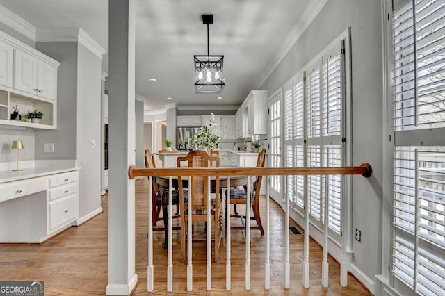 dining area with light wood-type flooring, a healthy amount of sunlight, and ornamental molding