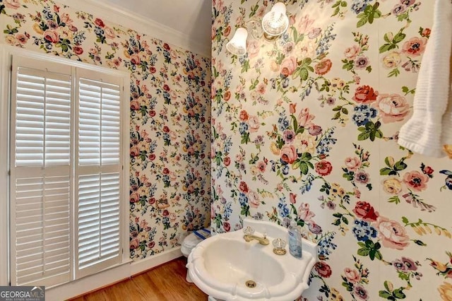 bathroom with a sink, baseboards, wood finished floors, and wallpapered walls