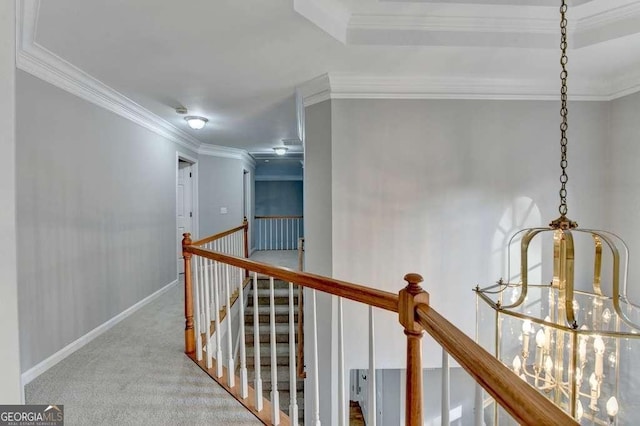 hall featuring crown molding, an upstairs landing, baseboards, and carpet floors