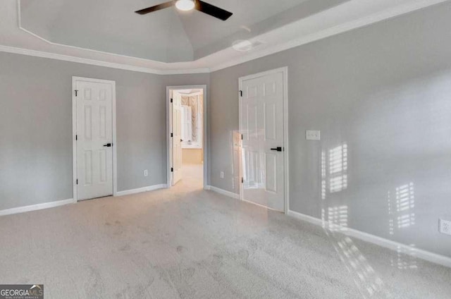 unfurnished bedroom with crown molding, carpet, baseboards, vaulted ceiling, and a raised ceiling