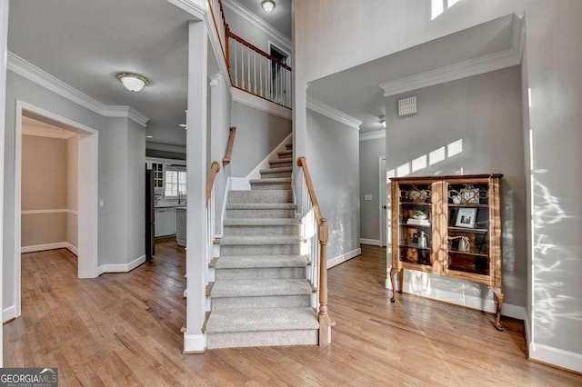 stairs with crown molding, wood finished floors, and baseboards