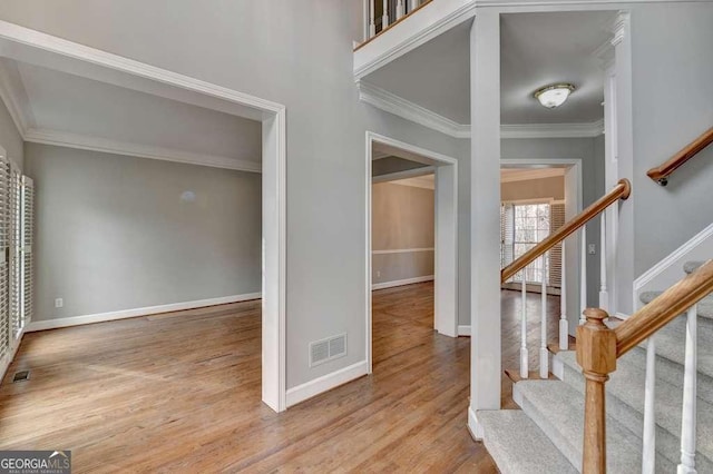 entryway featuring visible vents, baseboards, wood finished floors, and crown molding