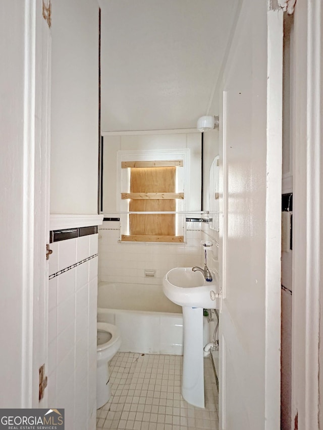 bathroom featuring tile patterned flooring, toilet, tile walls, and a sink