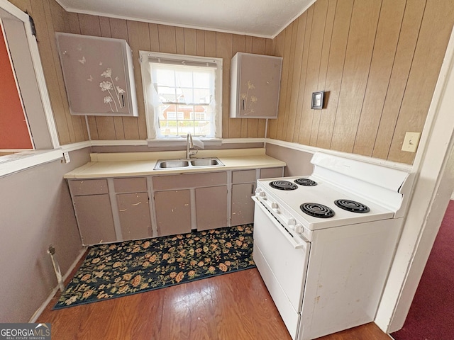 kitchen with crown molding, light countertops, light wood-style flooring, white electric stove, and a sink