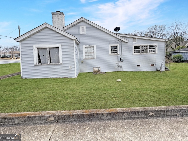 back of house with a yard and a chimney