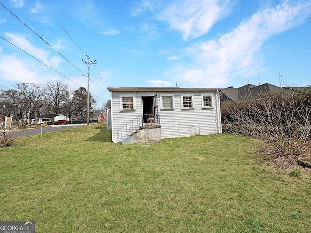 rear view of property with entry steps and a yard