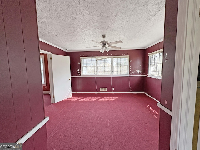 empty room featuring a ceiling fan, plenty of natural light, carpet, and visible vents