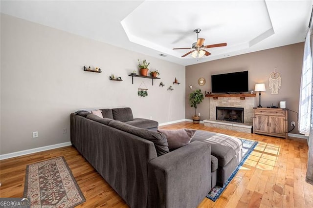 living room featuring ceiling fan, baseboards, and a tray ceiling