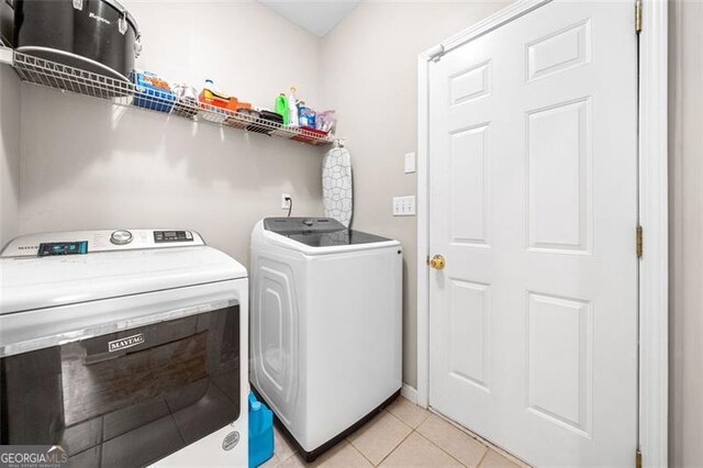 clothes washing area featuring independent washer and dryer, laundry area, and light tile patterned floors