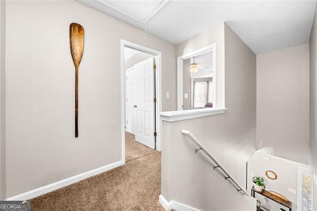 corridor with attic access, baseboards, light colored carpet, and an upstairs landing