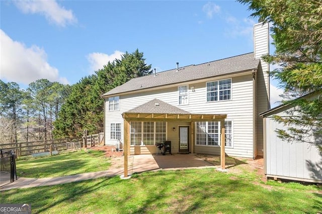 rear view of property with an outbuilding, a chimney, fence, a patio area, and a lawn