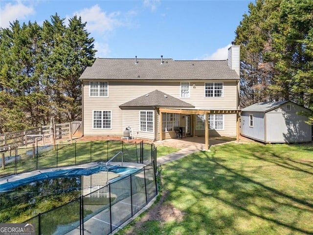 rear view of property featuring a storage unit, an outbuilding, a fenced backyard, a chimney, and a yard