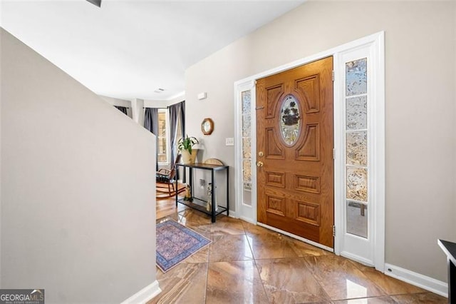 foyer entrance featuring marble finish floor and baseboards