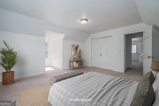 carpeted bedroom featuring vaulted ceiling, baseboards, and a closet