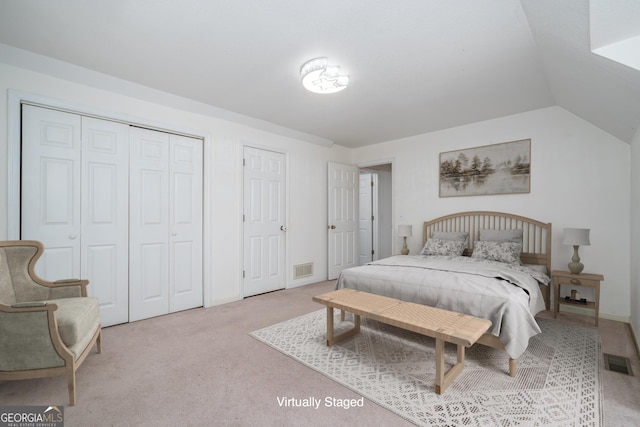 bedroom featuring lofted ceiling, visible vents, two closets, and carpet floors