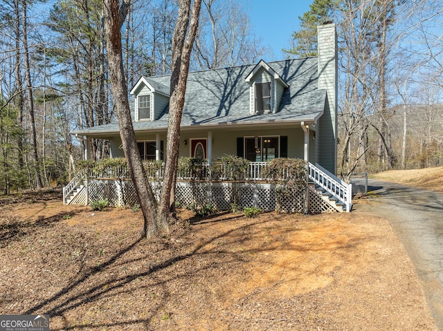 new england style home with stairway, a porch, a chimney, and driveway