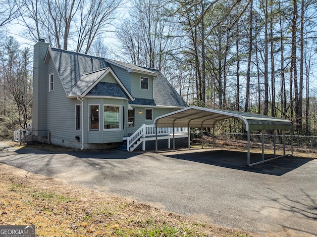 view of front facade featuring crawl space, a detached carport, a shingled roof, and aphalt driveway