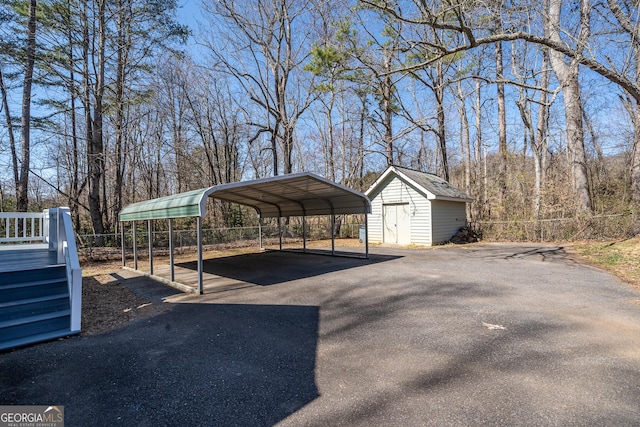 view of patio / terrace featuring a detached carport, fence, an outbuilding, and driveway