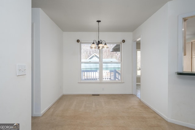 unfurnished dining area featuring visible vents, baseboards, light colored carpet, and an inviting chandelier