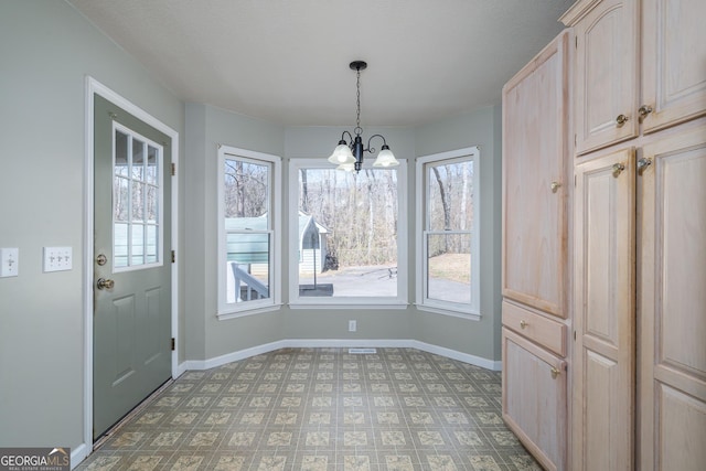 unfurnished dining area featuring baseboards, light floors, and an inviting chandelier