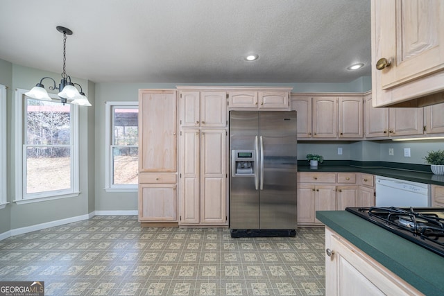 kitchen with dark countertops, stovetop, white dishwasher, stainless steel fridge with ice dispenser, and a chandelier