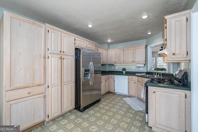 kitchen featuring dark countertops, light floors, recessed lighting, stainless steel appliances, and a sink