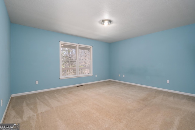 spare room featuring visible vents, baseboards, and carpet