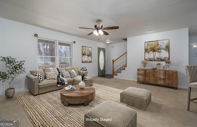 living area with a textured ceiling, baseboards, stairs, and a ceiling fan